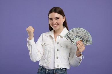 Photo of Excited woman with dollar banknotes on purple background