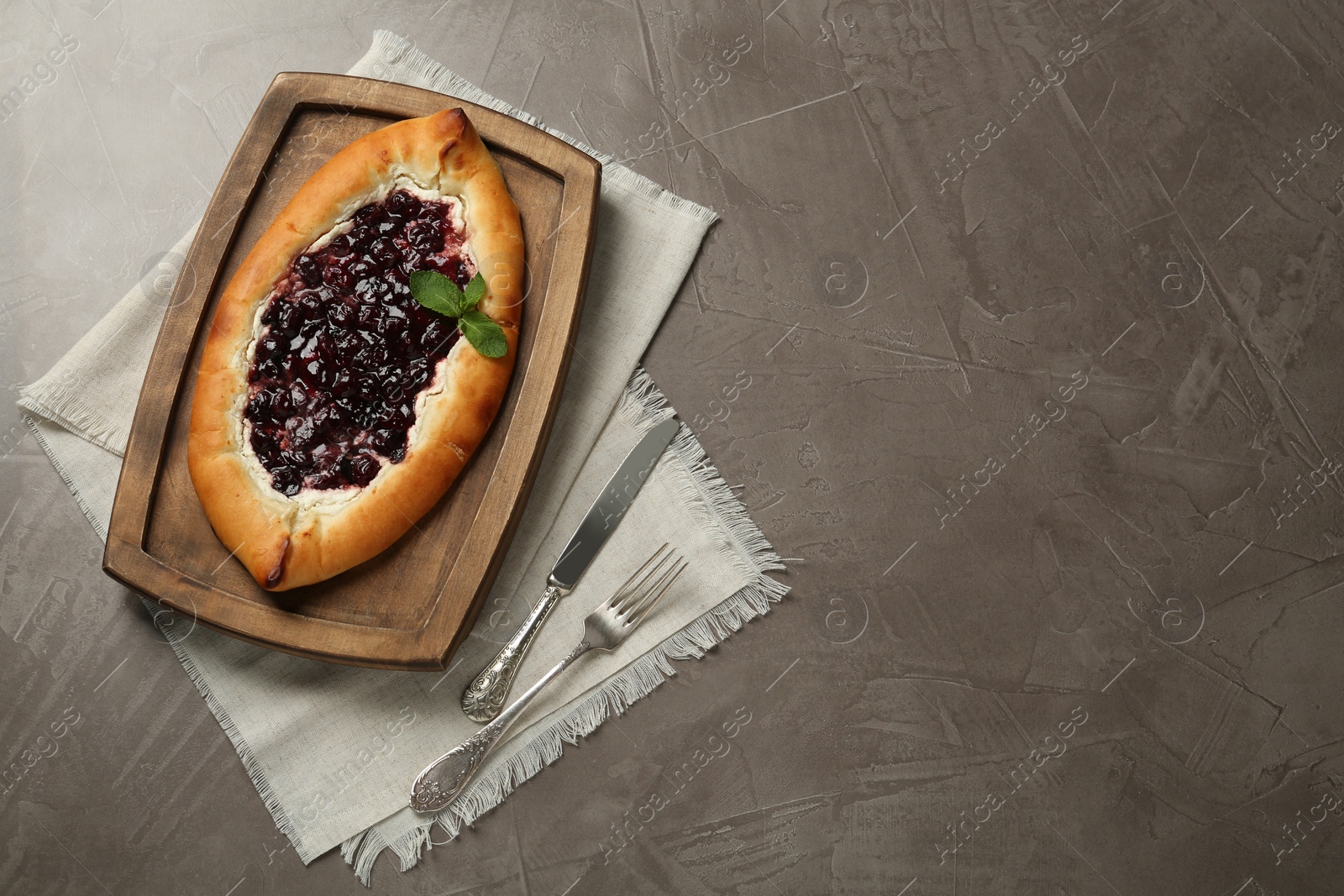 Photo of Delicious sweet cottage cheese pastry with cherry jam served on grey table, flat lay. Space for text