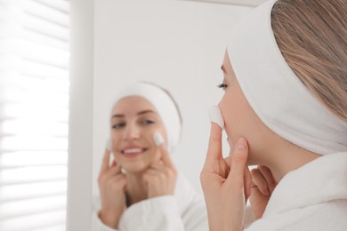 Photo of Woman using silkworm cocoons in skin care routine near mirror at home