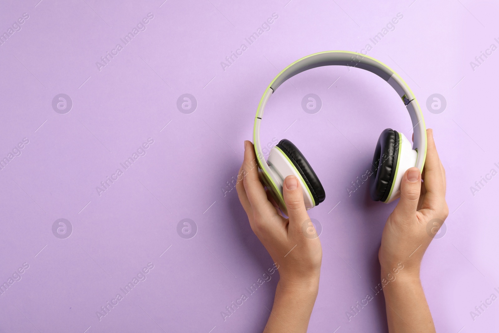 Photo of Woman holding headphones on color background, top view. Space for text