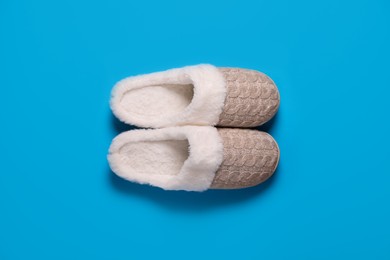 Pair of beautiful soft slippers on light blue background, top view