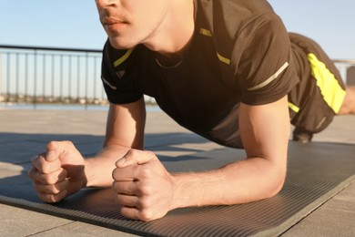 Photo of Sporty man doing plank exercise outdoors, closeup