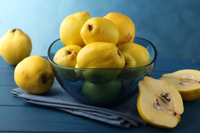 Photo of Tasty ripe quinces in bowl on blue wooden table, closeup