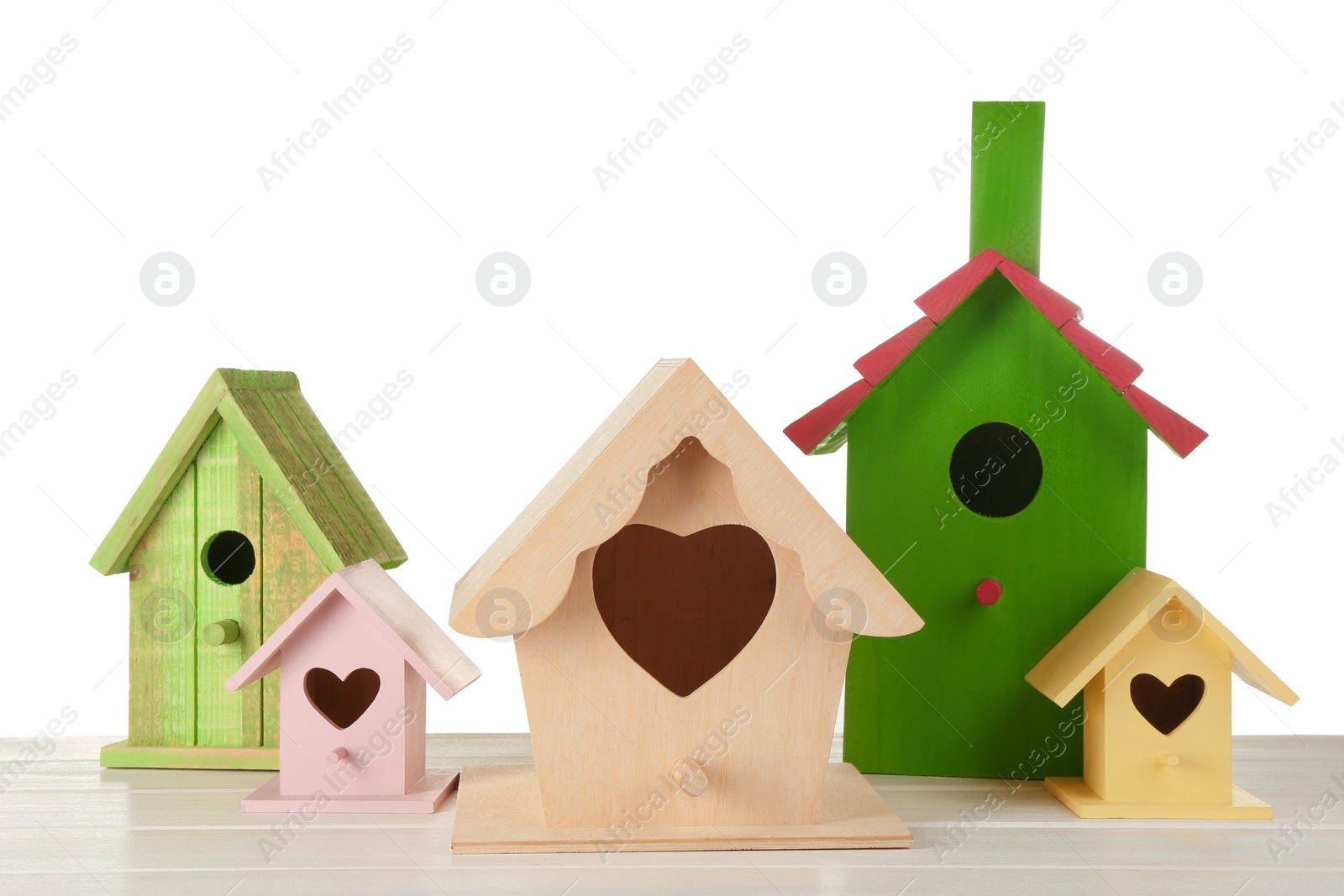 Photo of Many different bird houses on wooden table against white background