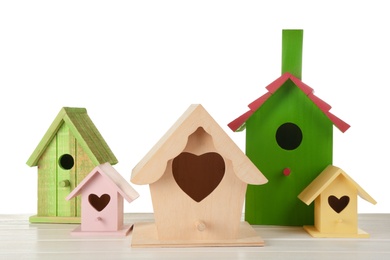 Many different bird houses on wooden table against white background