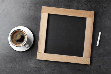 Photo of Clean small blackboard, chalk and cup of coffee on grey table, flat lay