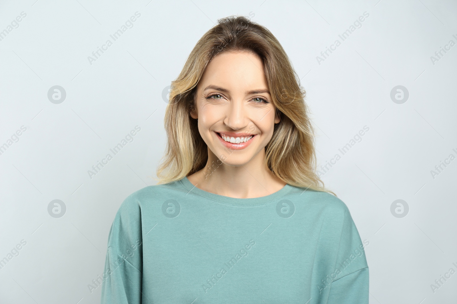 Photo of Portrait of happy young woman with beautiful blonde hair and charming smile on light background