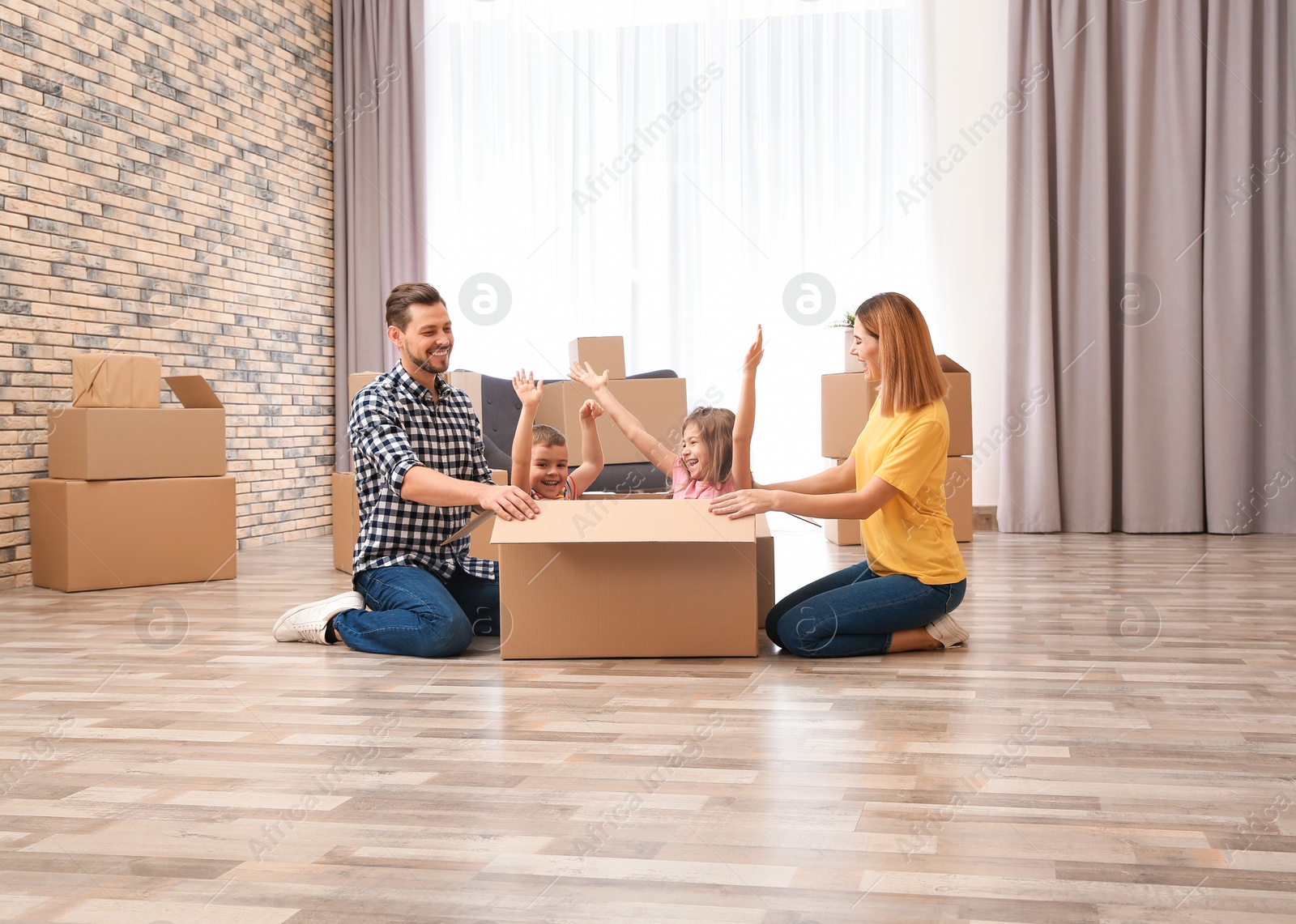 Photo of Happy family playing with cardboard box in their new house. Moving day