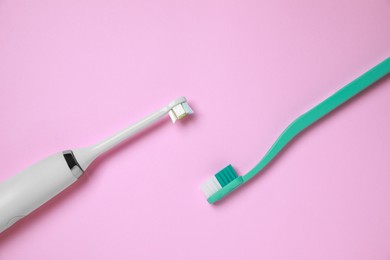 Photo of Electric and plastic toothbrushes on pink background, flat lay