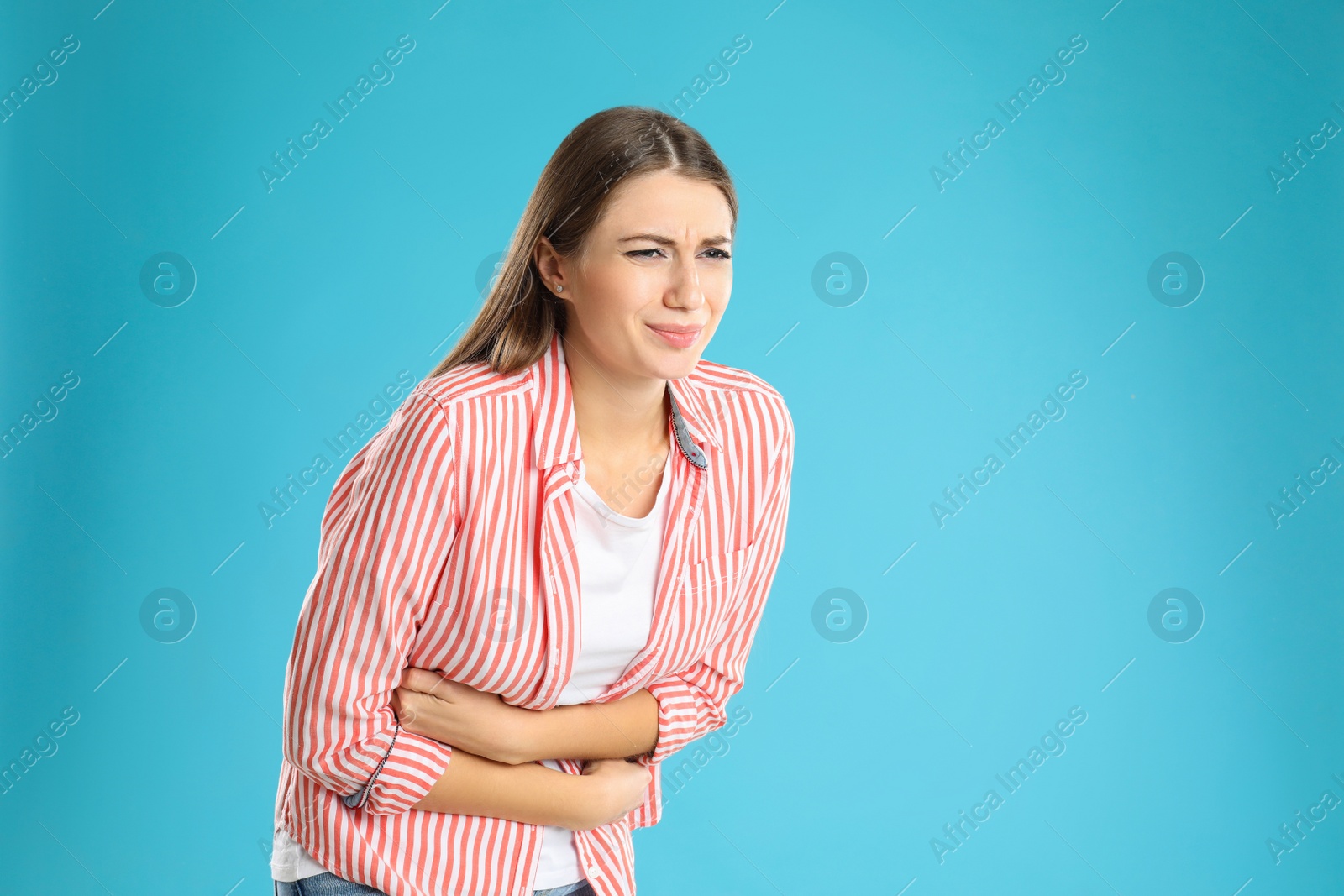 Photo of Woman suffering from stomach ache on light blue background, space for text. Food poisoning