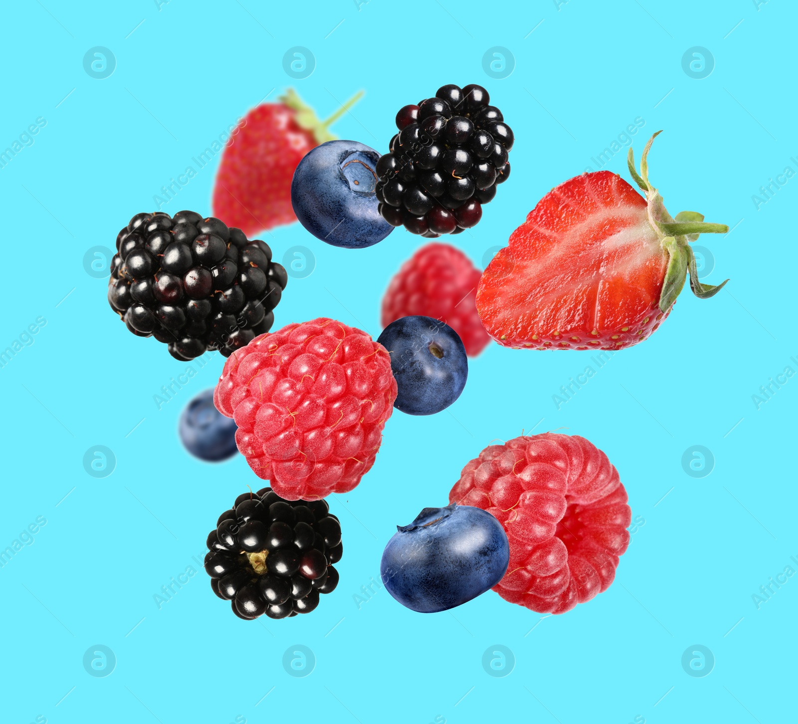 Image of Many different fresh berries falling on light blue background