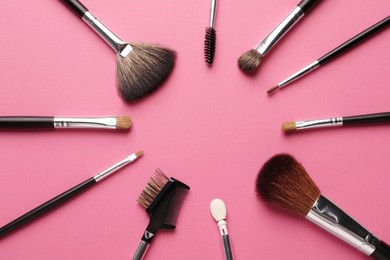 Photo of Frame of makeup brushes on pink background, flat lay. Space for text