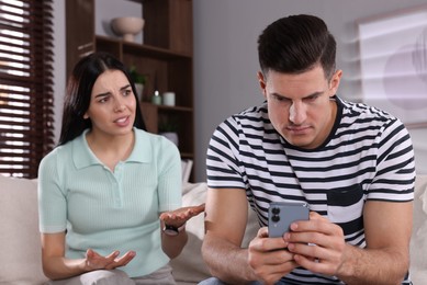 Photo of Internet addiction. Man with smartphone ignoring his girlfriend in living room