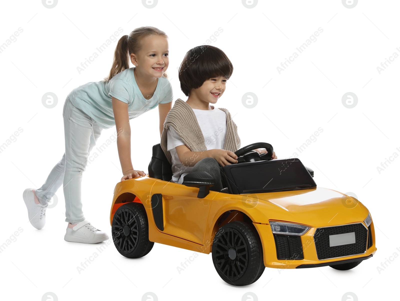 Photo of Cute girl pushing children's electric toy car with little boy on white background