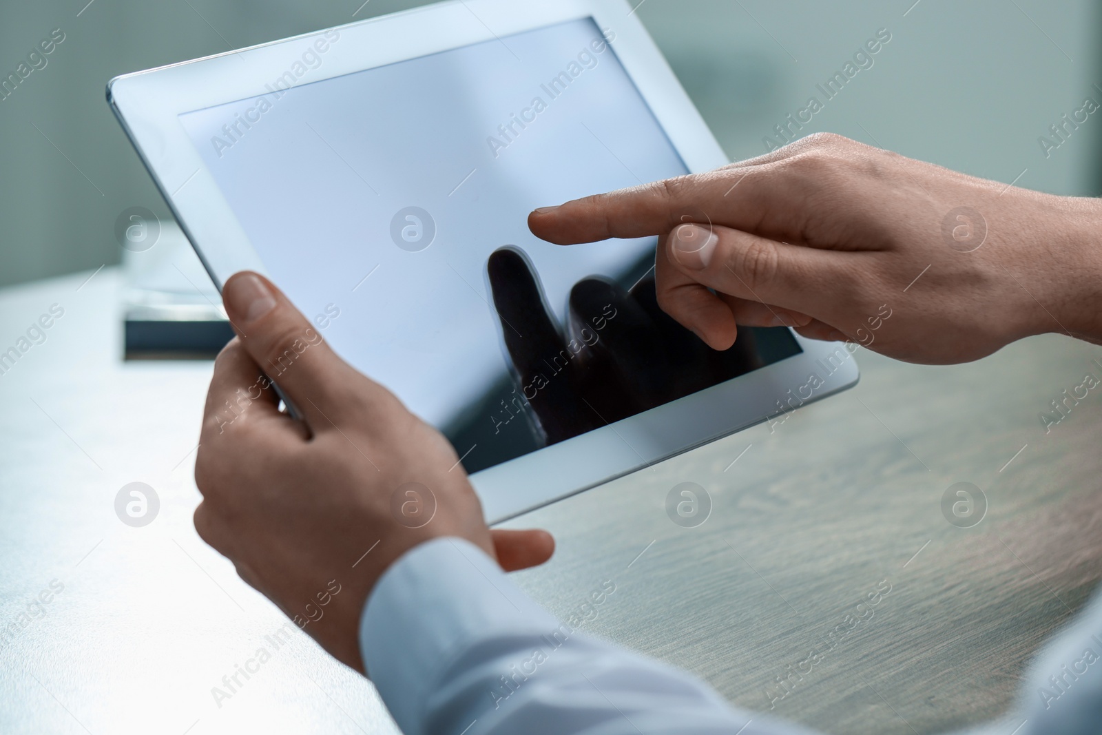 Photo of Man using tablet at wooden table, closeup