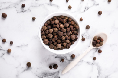 Photo of Black peppercorns on white marble table, flat lay