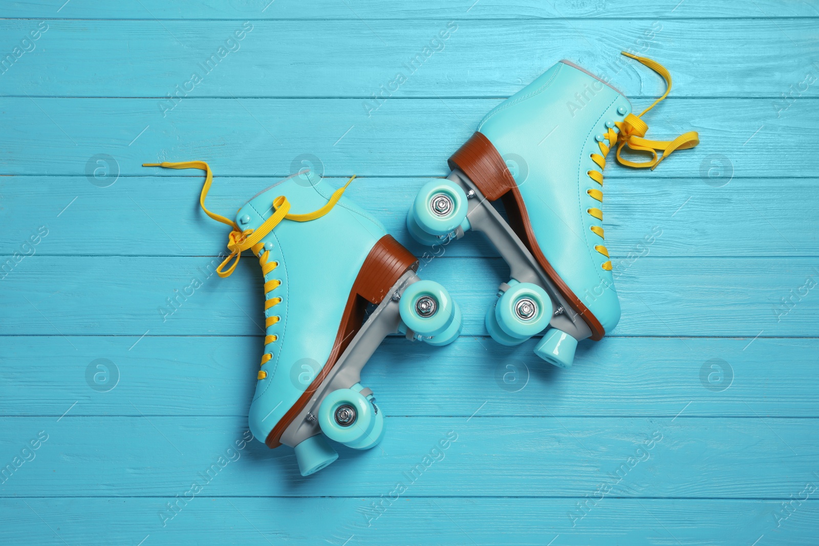 Photo of Pair of stylish quad roller skates on wooden background, top view