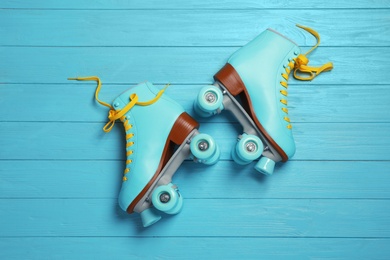 Photo of Pair of stylish quad roller skates on wooden background, top view