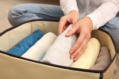 Woman folding clothes on floor, closeup. Japanese storage system
