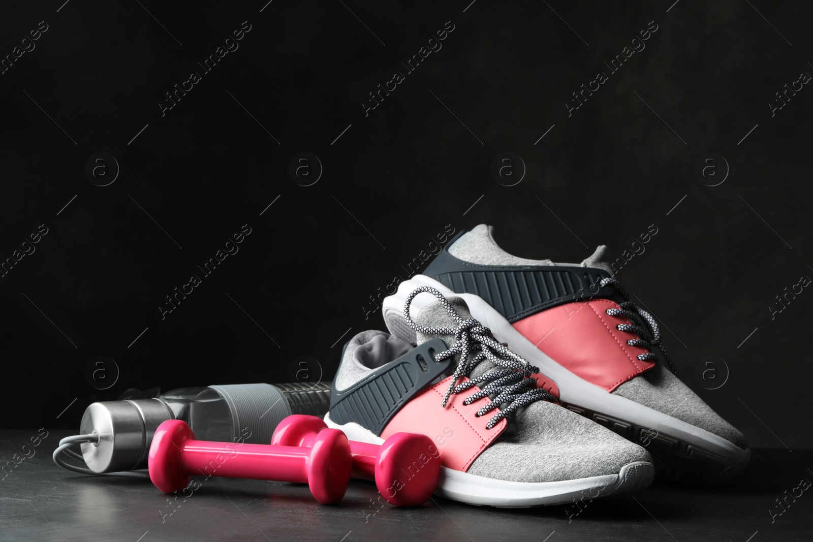 Gym equipment and accessories on stone floor against dark background Photo of Gym equipment and accessories on stone floor against dark background