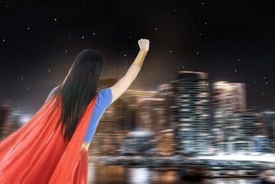 Image of Young woman wearing superhero costume and beautiful cityscape in night on background