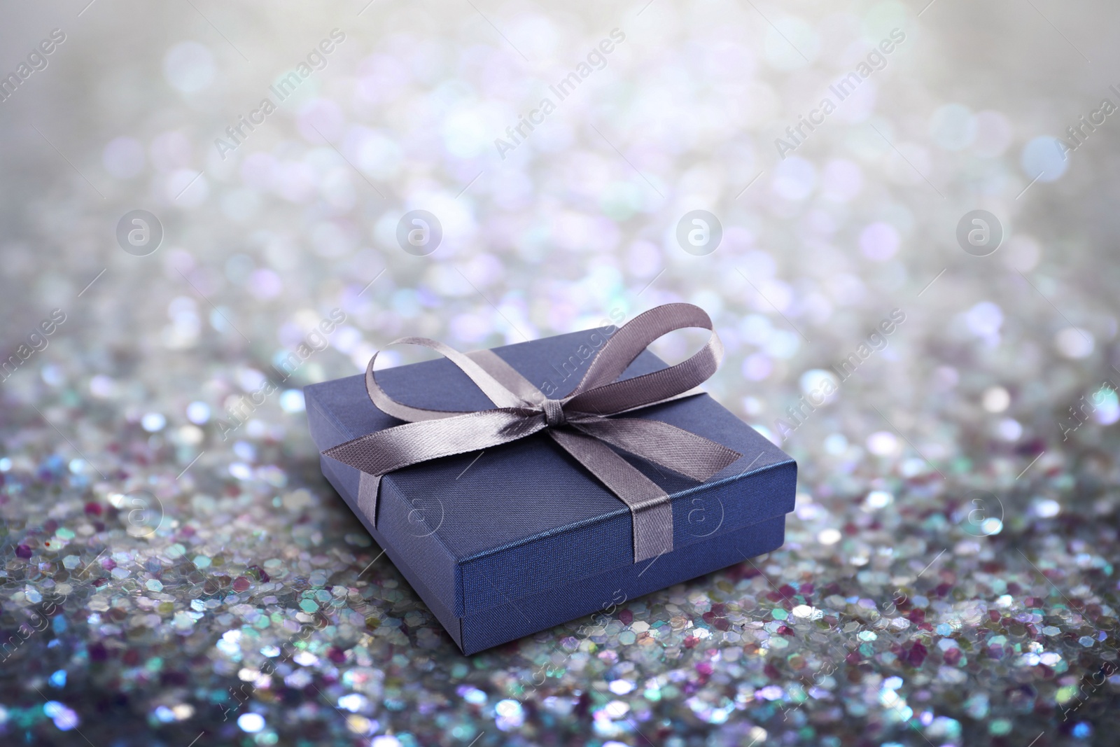 Image of Beautiful gift box on shiny silver glitters. Bokeh effect 