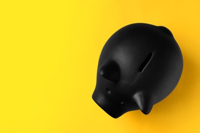Photo of Ceramic piggy bank on yellow background, top view. Space for text