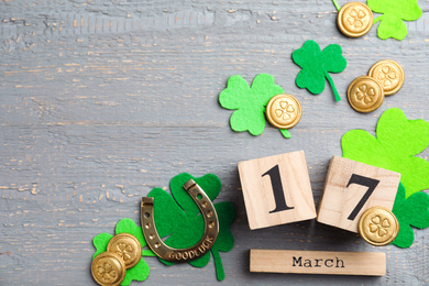 Flat lay composition with horseshoe and block calendar on grey wooden background, space for text. St. Patrick's Day celebration