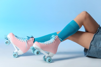 Photo of Woman with vintage roller skates on color background, closeup