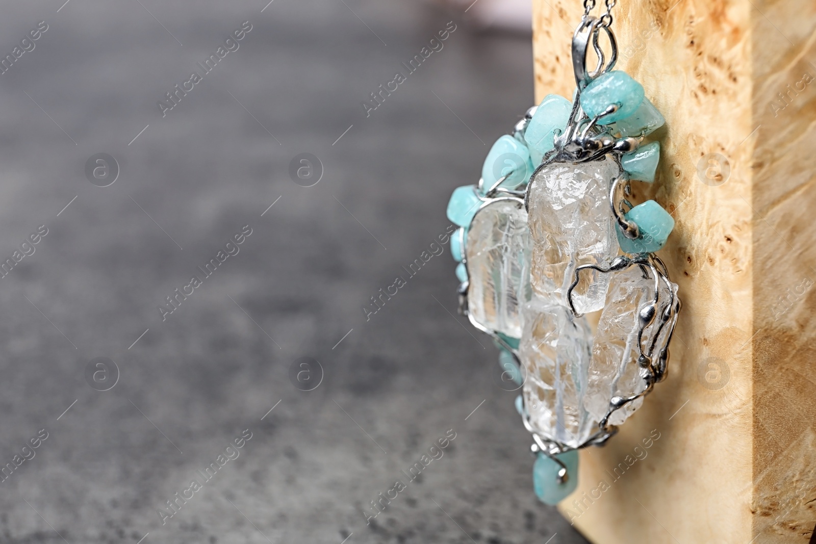 Photo of Beautiful silver pendent with pure quartz gemstones on grey table. Space for text