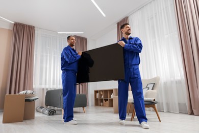 Male movers carrying plasma TV in new house