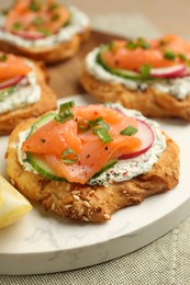 Tasty canapes with salmon, cucumber, radish and cream cheese on table, closeup