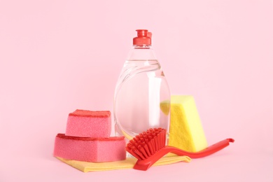 Cleaning supplies for dish washing on pink background