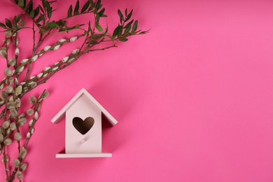 Photo of Stylish bird house and fresh pussy willow branches on pink background, flat lay. Space for text