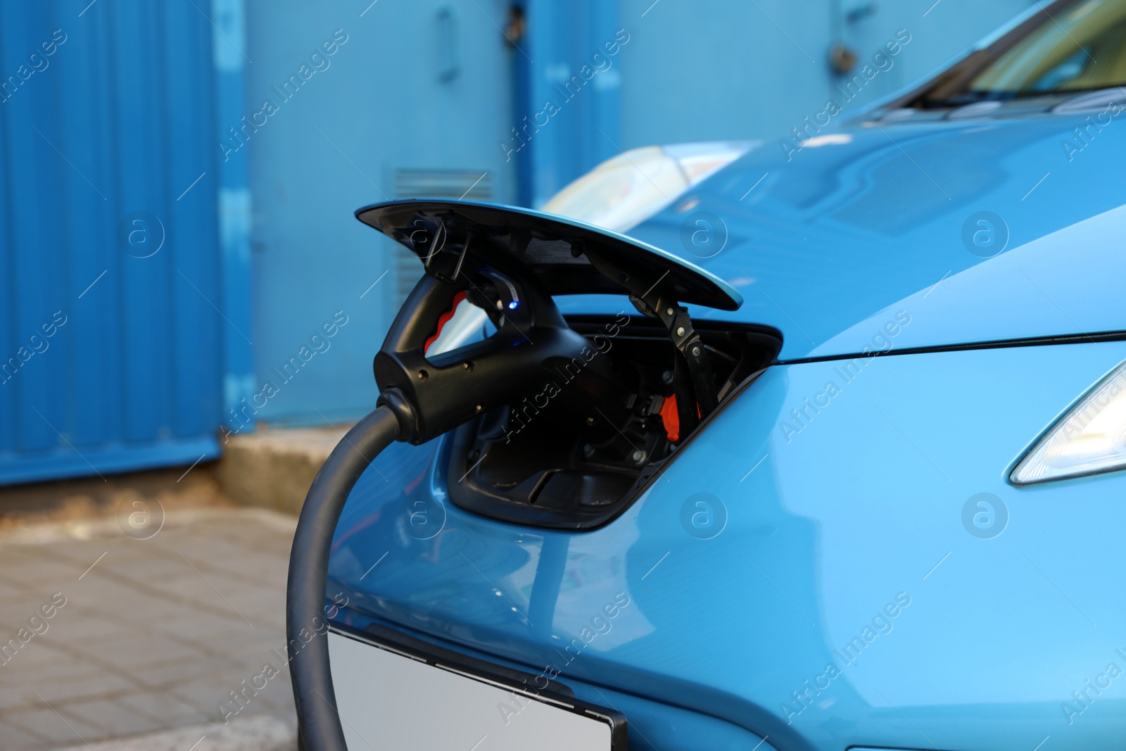 Photo of Charging modern electric car from station outdoors, closeup