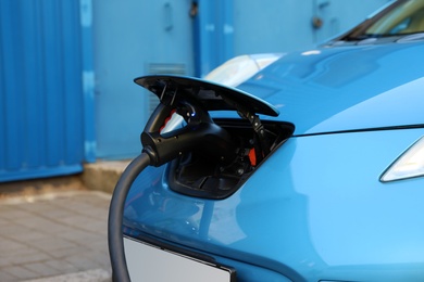 Photo of Charging modern electric car from station outdoors, closeup