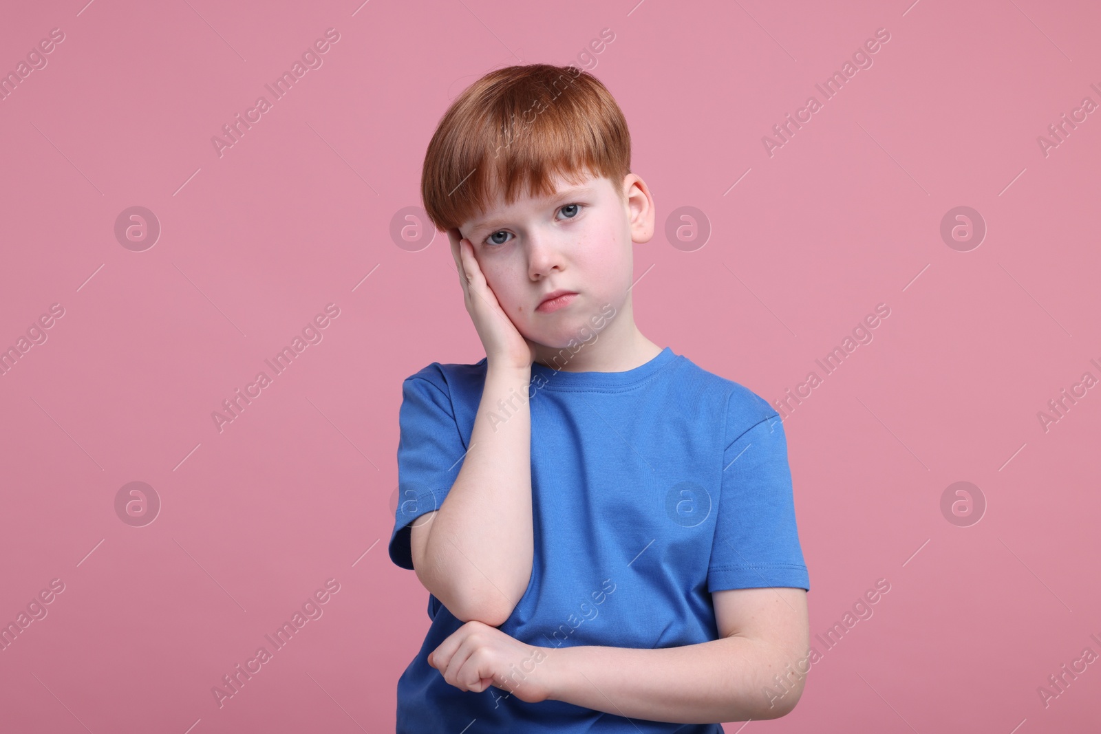 Photo of Portrait of sad little boy on pink background