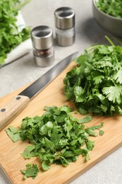 Photo of Fresh green cilantro and knife on light grey table, closeup
