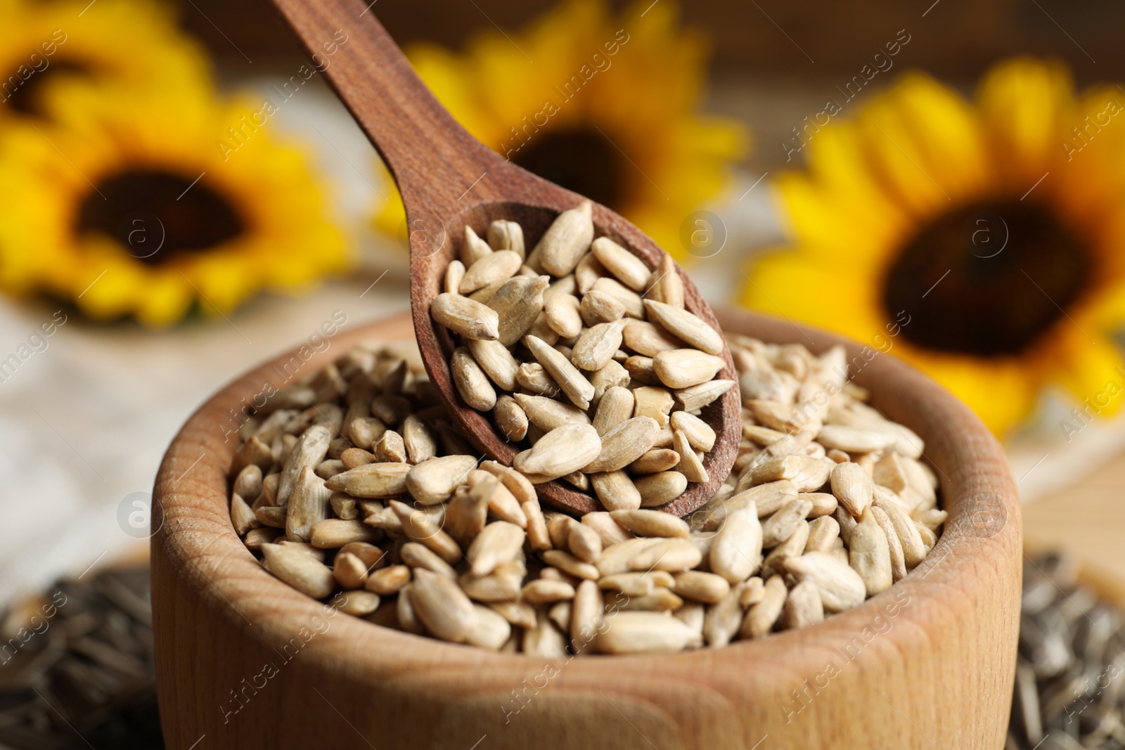 Photo of Raw peeled sunflower seeds in wooden bowl, closeup