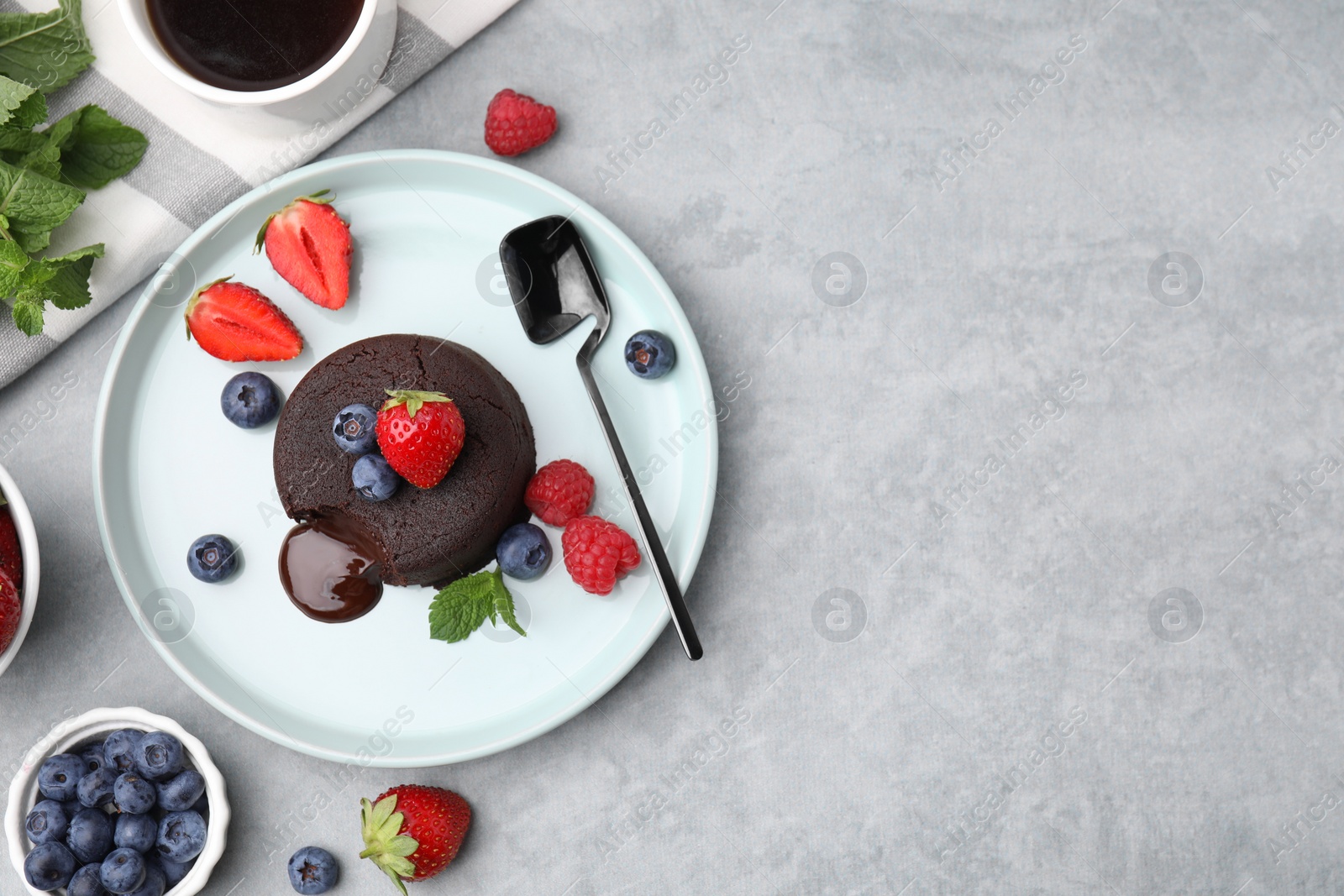 Photo of Plate with delicious chocolate fondant, berries and mint on grey table, flat lay. Space for text