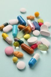 Photo of Pile of different pills on mint background, selective focus
