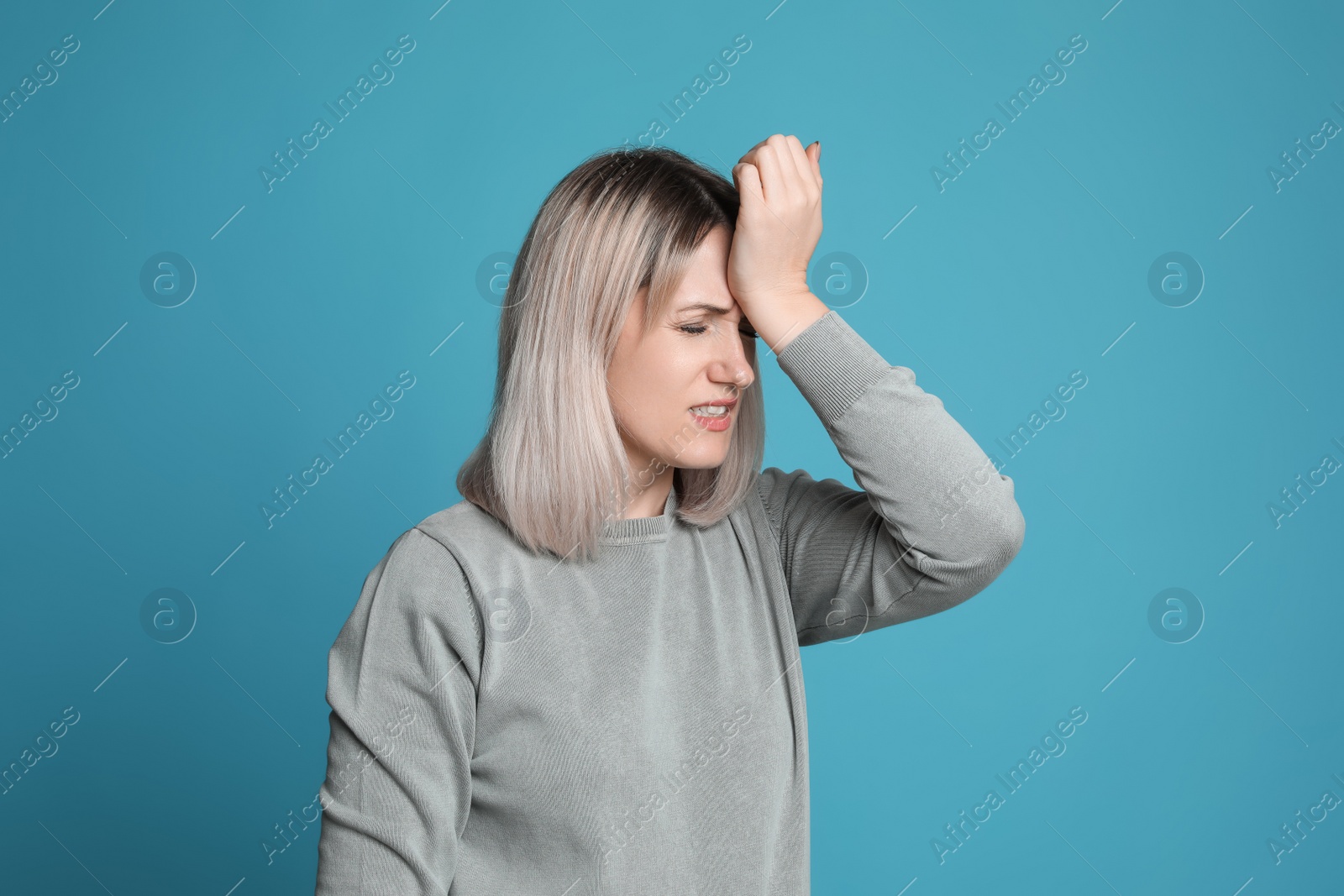 Photo of Woman suffering from headache on light blue background