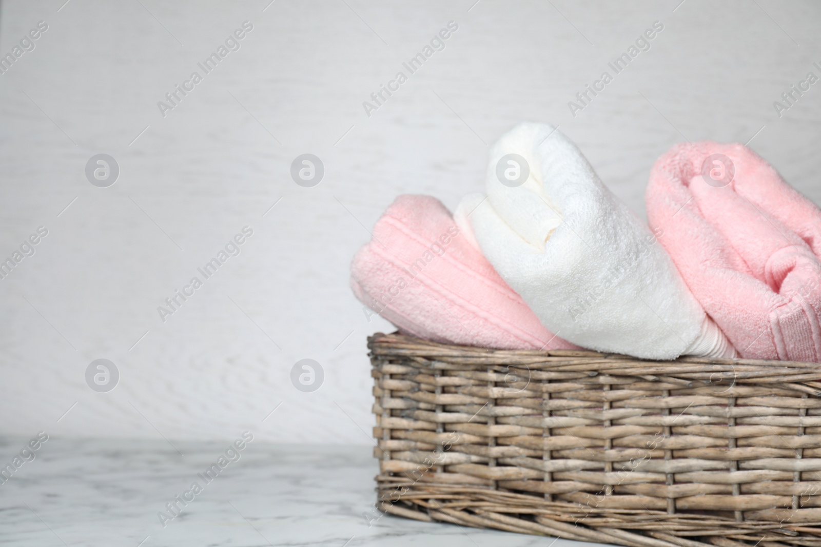 Photo of Basket with soft bath towels on table. Space for text