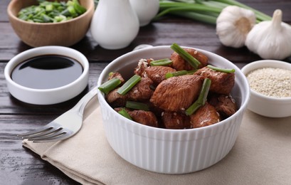 Tasty soy sauce and roasted meat on wooden table, closeup