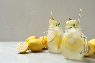 Photo of Natural lemonade with mint and fresh fruits on light grey marble table, space for text. Summer refreshing drink