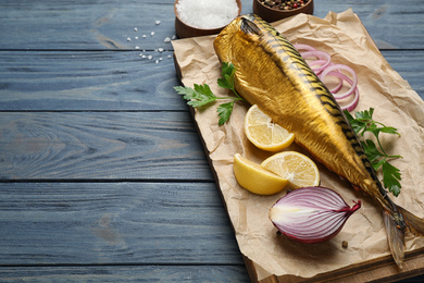 Tasty smoked fish on blue wooden table. Space for text