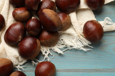 Photo of Roasted edible sweet chestnuts on light blue wooden table, flat lay