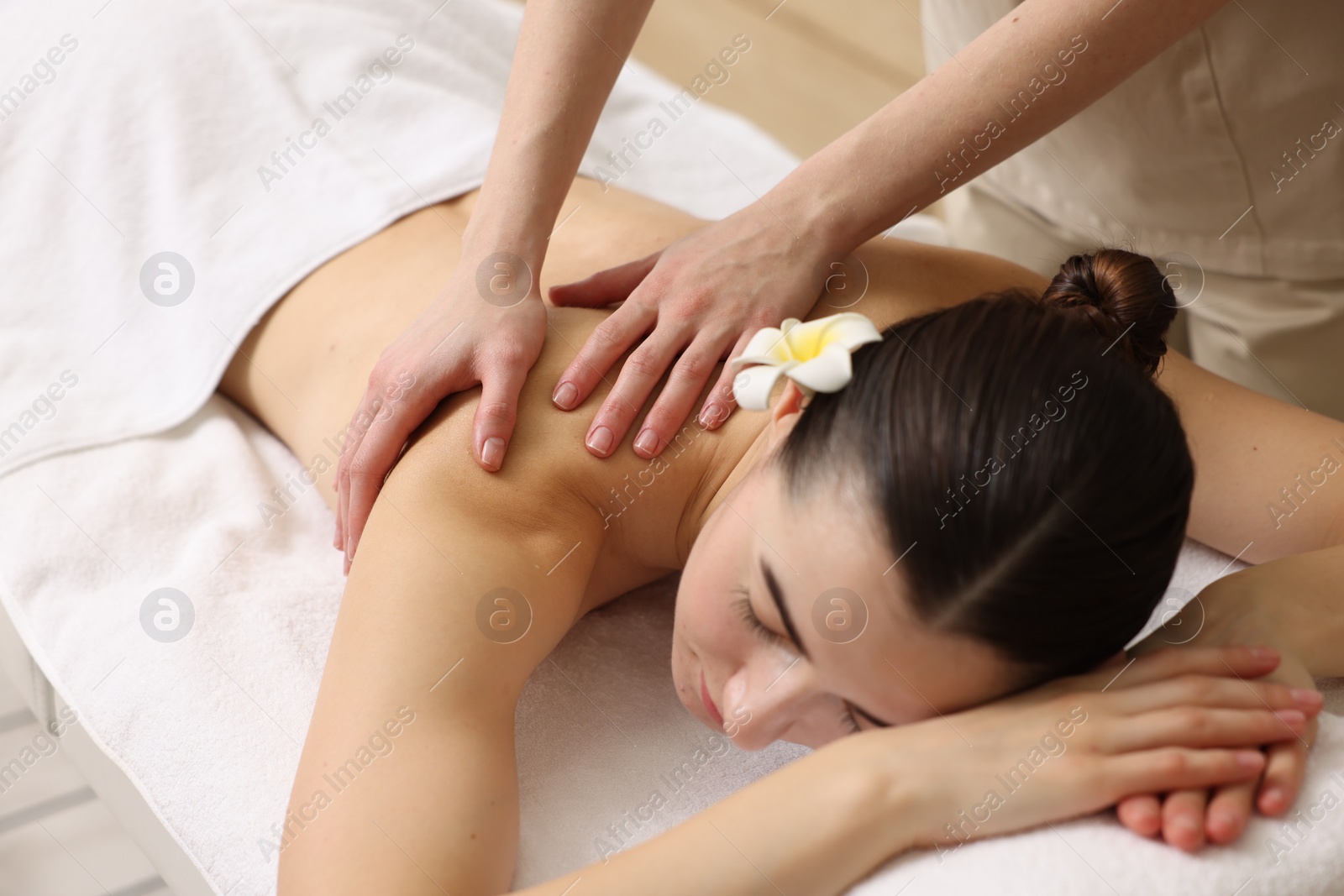 Photo of Woman receiving back massage on couch in spa salon