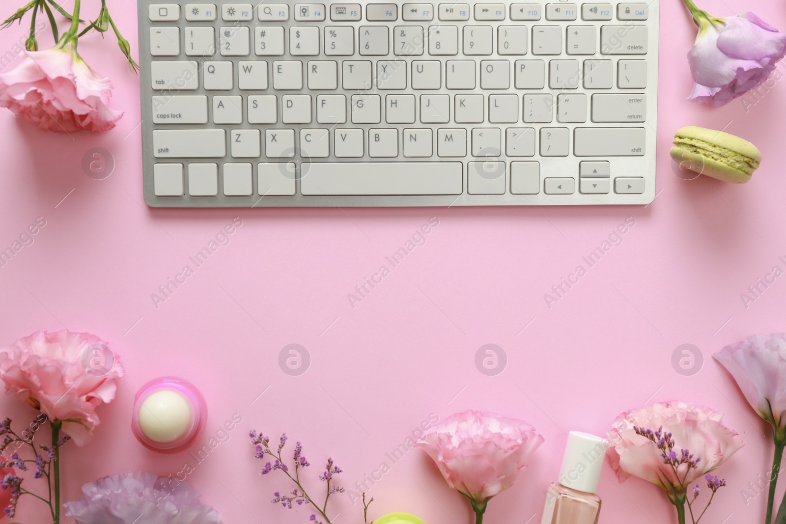 Photo of Flat lay composition with keyboard and flowers on pink background. Beauty blogger's workplace