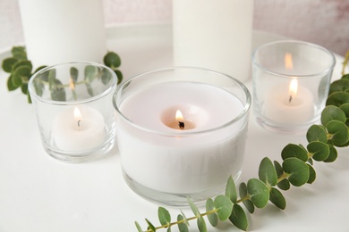 Photo of Composition with burning aromatic candles and eucalyptus on table